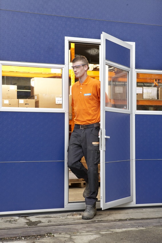 Schlupftür in blauem Compact Falttor in einer Produktionshalle Schlupftür in blauem Compact Falttor in einer Produktionshalle