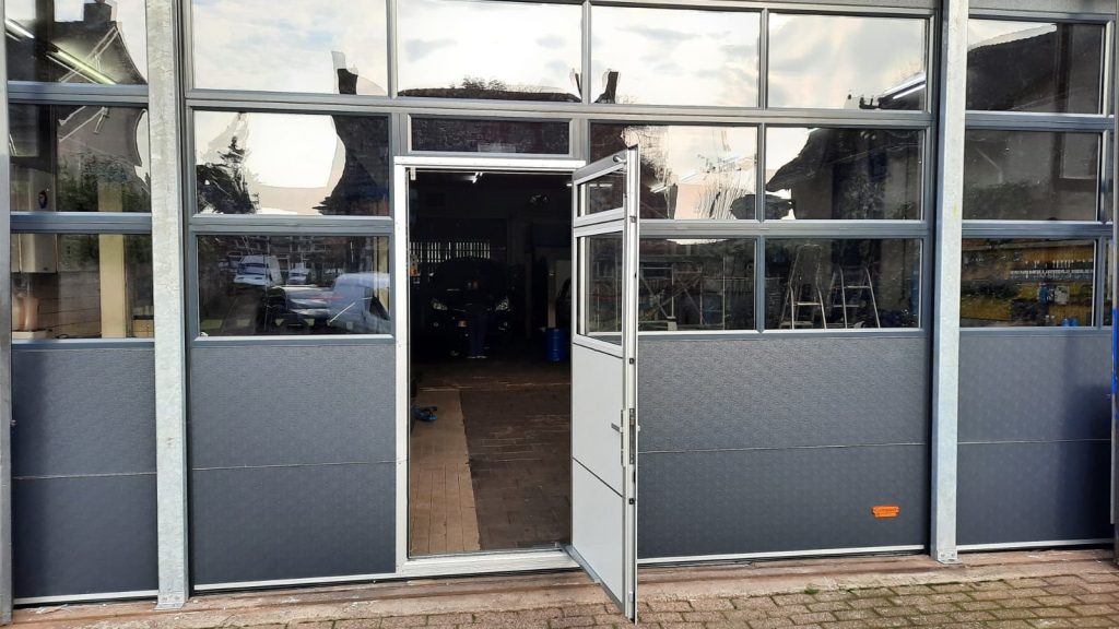 Geöffnete Schlupftür in einem anthrazit farbenen Compact Tor mit Fenstern
Sektionaltor mit Schlupftür und Lichtband