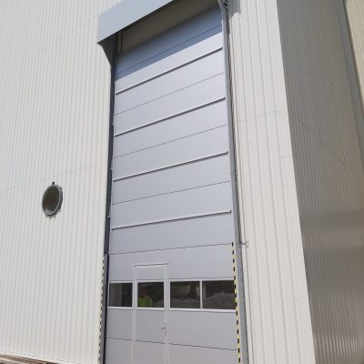 Buitenmontage van hoge Compact roldeuren met deur en stormprofielen bij Fermacell - Overheaddeur met loopdeur Rolflex